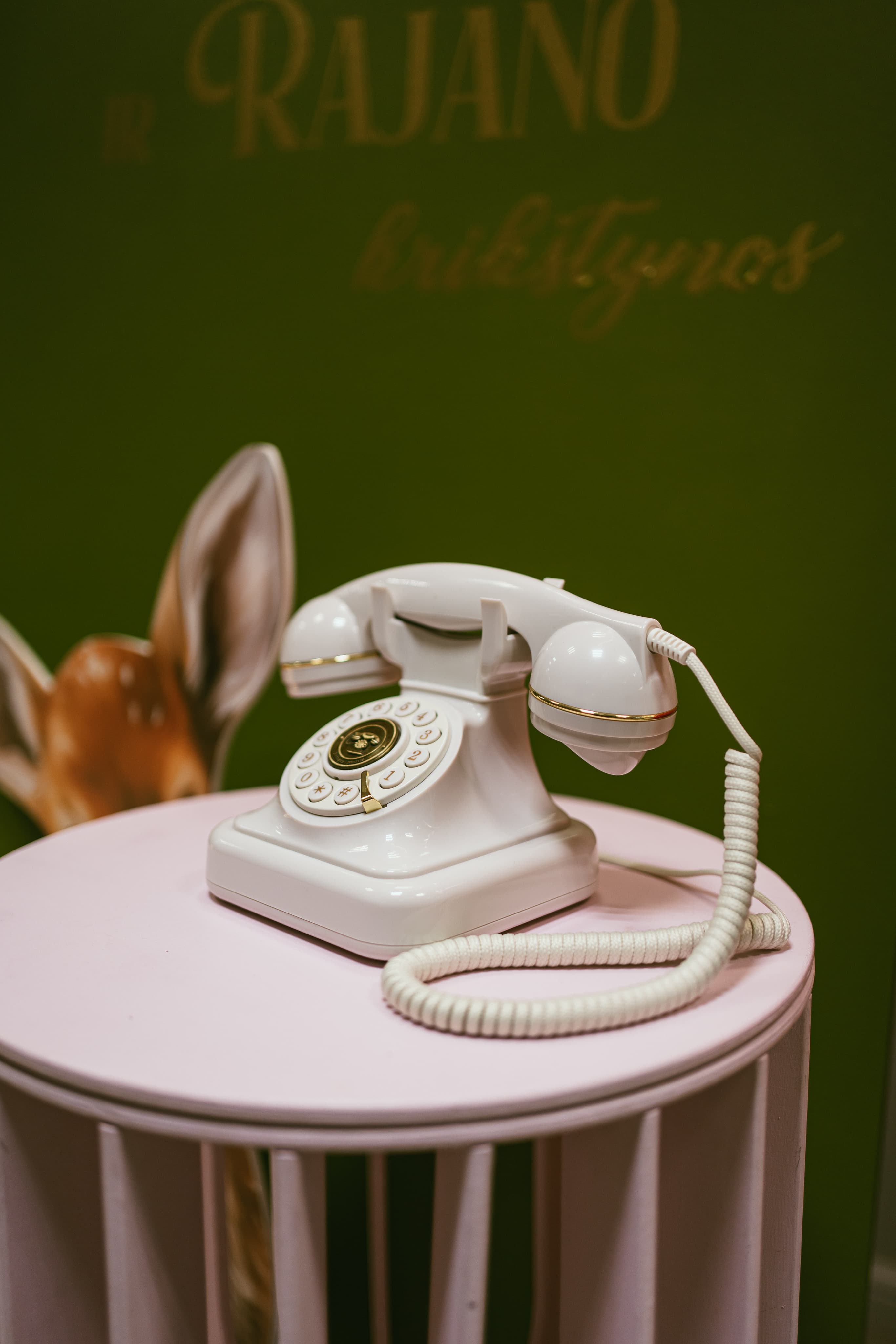 Baltas retro telefonas ant rausvo staliuko šventėje